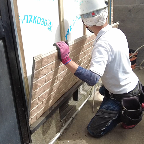 外壁にサイディングを貼り付けている人の写真